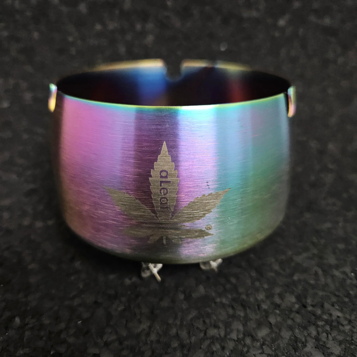 Rainbow titanium bowl with engraved leaf design on textured black background