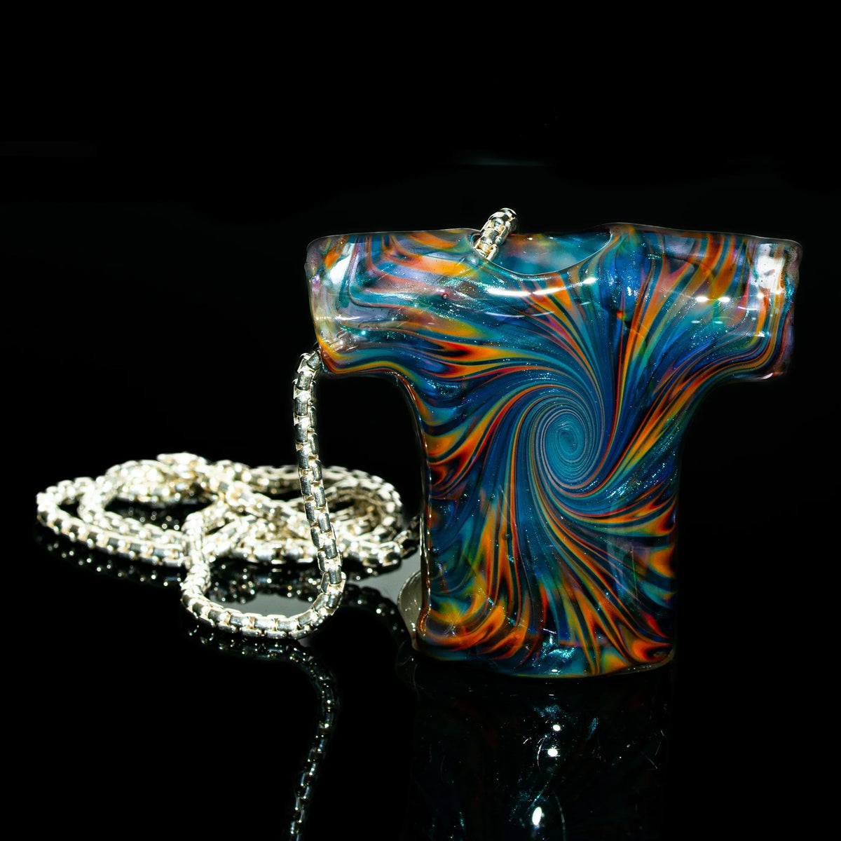 Colorful glass pendant shaped like a t-shirt with a swirl design on a silver chain