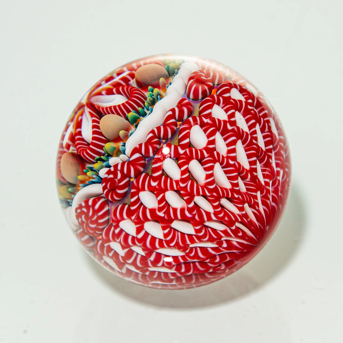 Heady glass marble with intricate red, white, and colorful cane design on white background