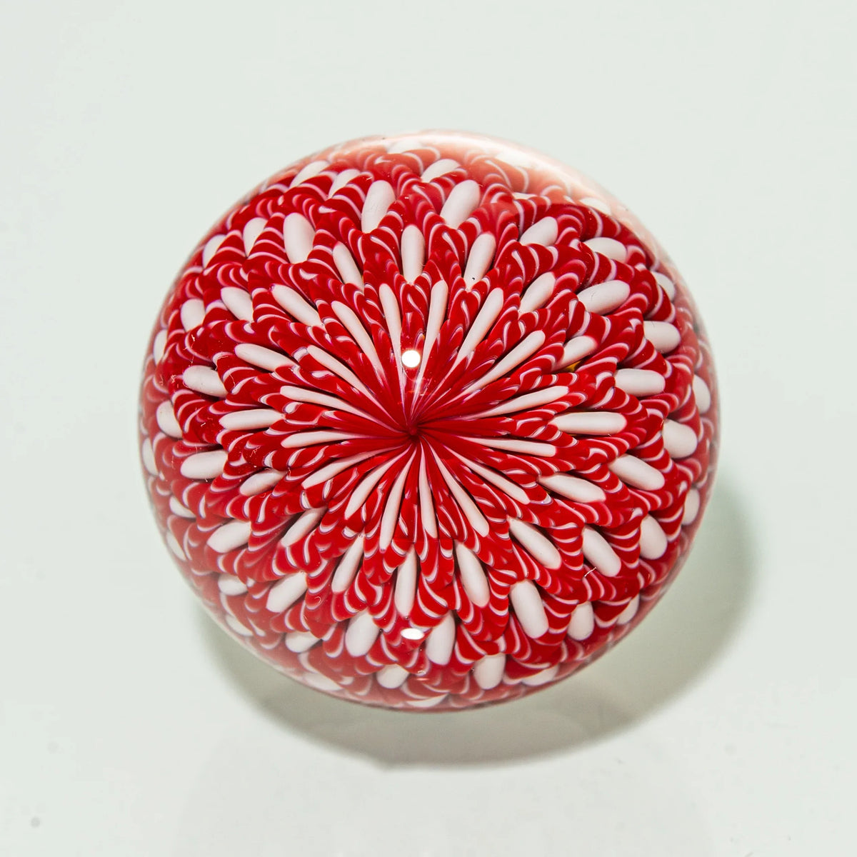 Red and white heady glass marble with intricate swirling flower pattern on a white background.