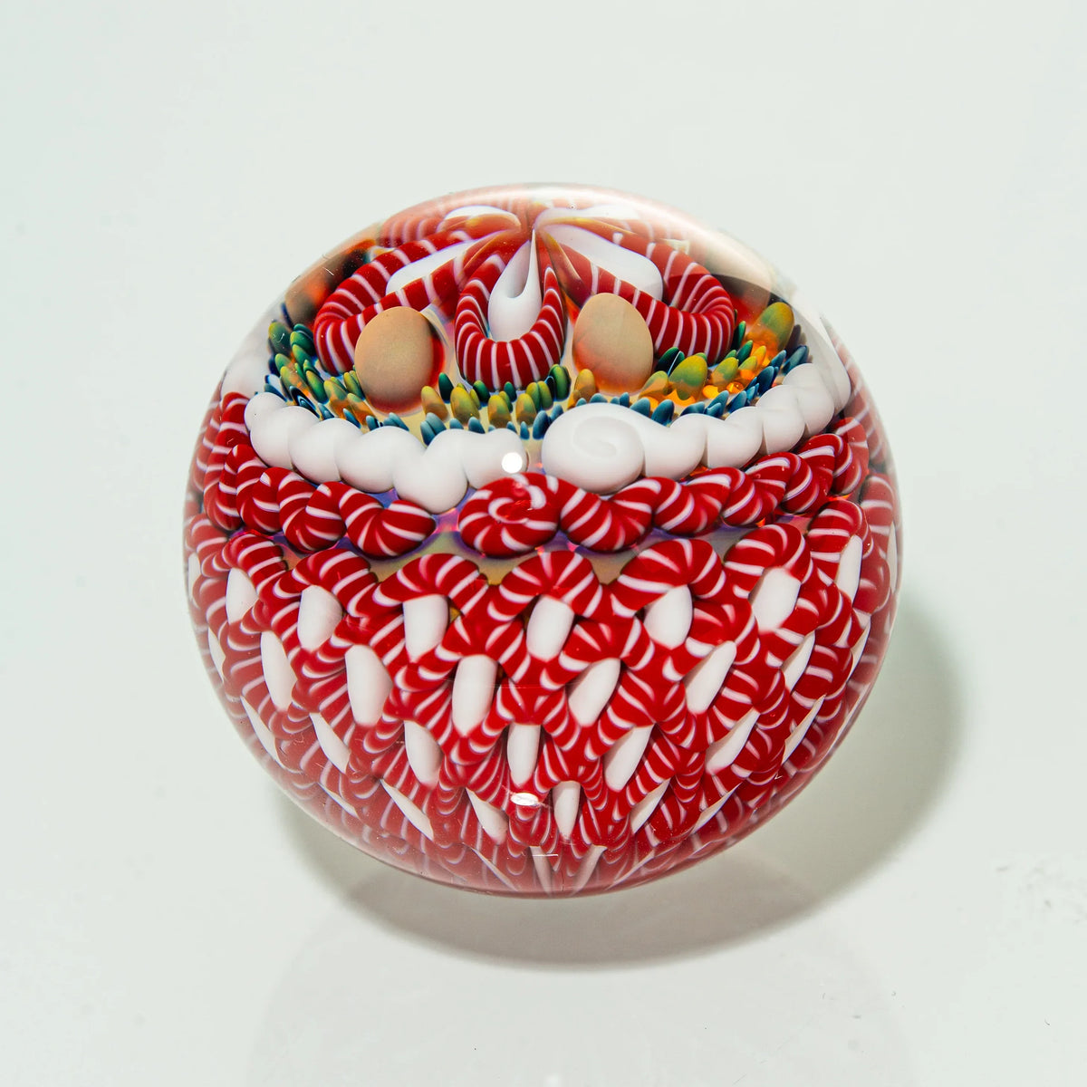 Intricate glass art marble with red, white, and colorful candy swirl patterns