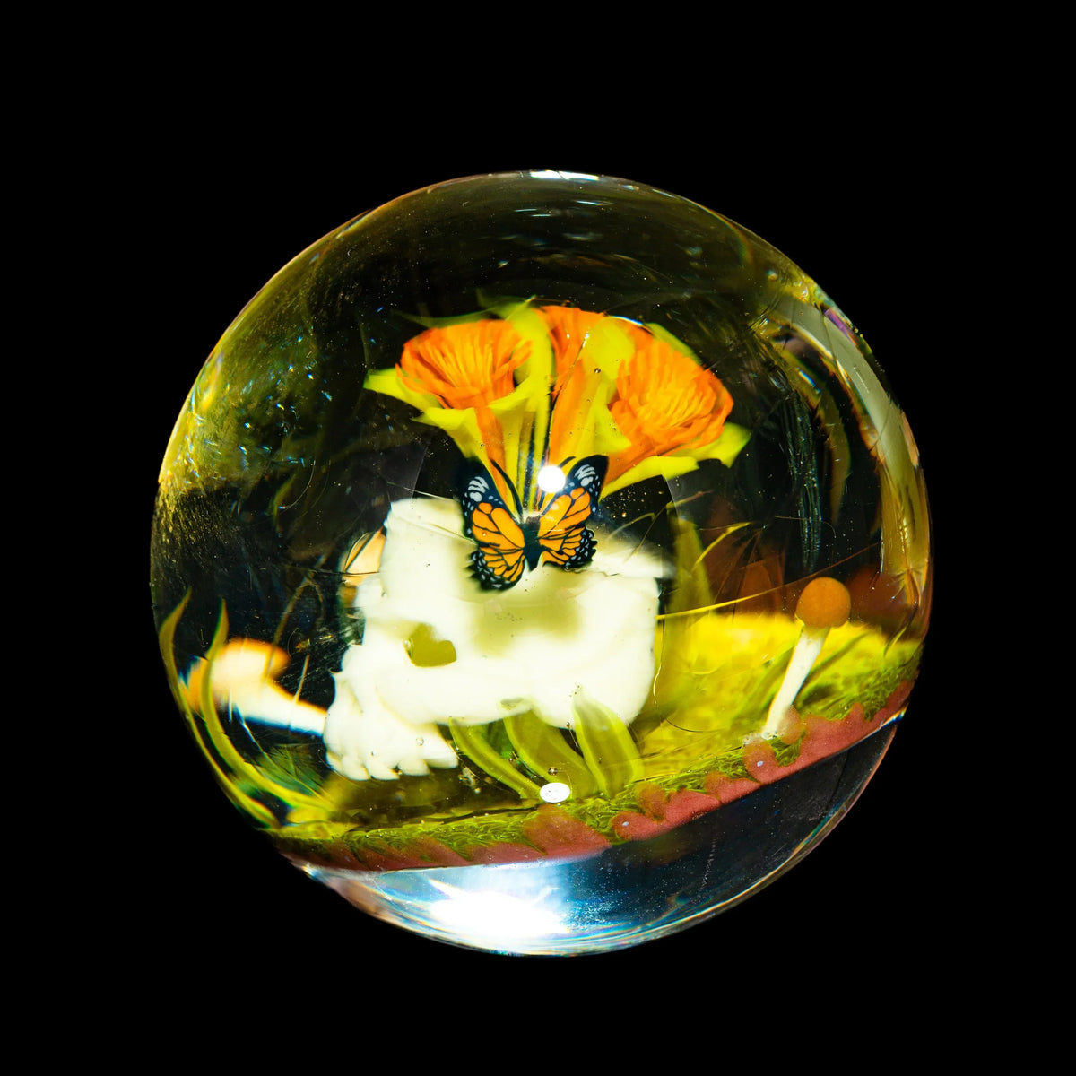 Heady glass marble with skull, butterfly, and orange flower design inside.
