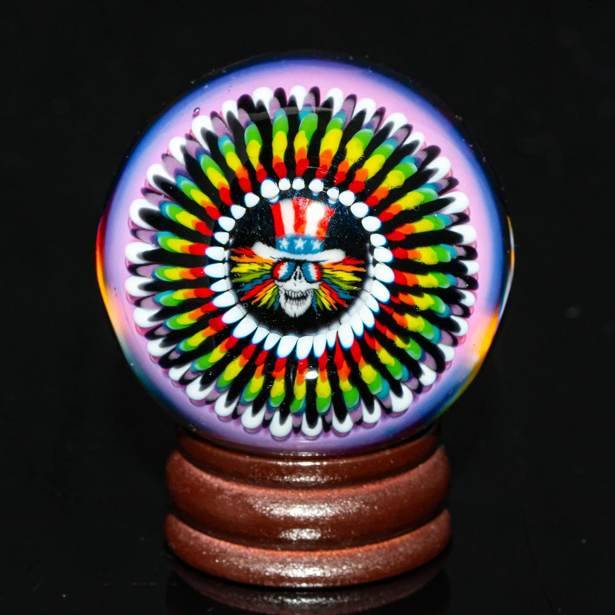 Colorful glass marble with psychedelic skull design on wooden stand, heady glass art