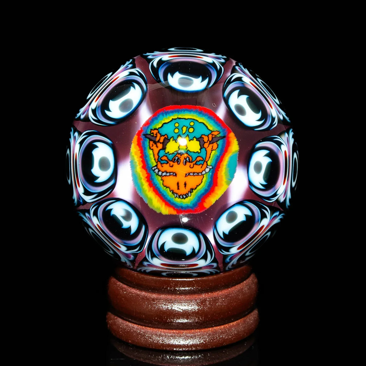 Heady glass marble with psychedelic dragon design and colorful patterns on wooden stand