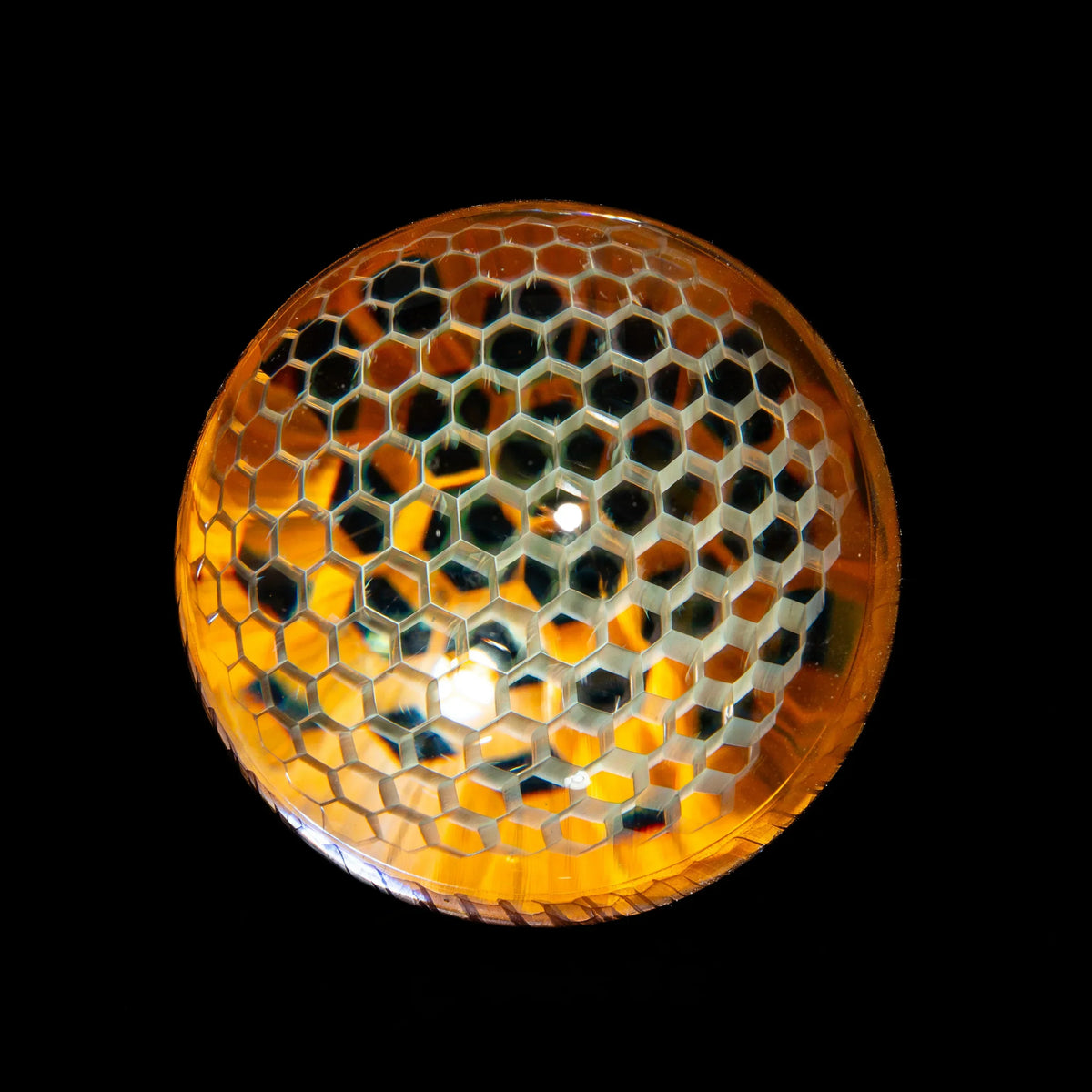 Artistic glass marble with honeycomb pattern and amber colors on black background