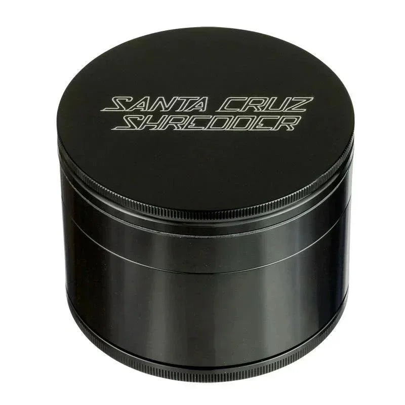 Black four-piece metal herb grinder with etched logo on lid, isolated on white background.