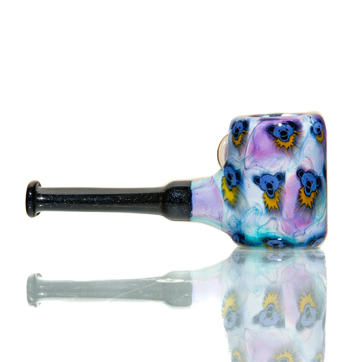 Colorful glass hand pipe with cartoon bear designs and black stem on reflective surface
