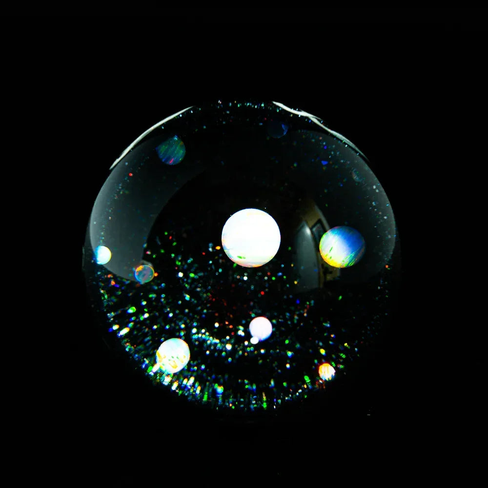 Handcrafted galaxy glass marble with opal planets and cosmic shimmer on black background