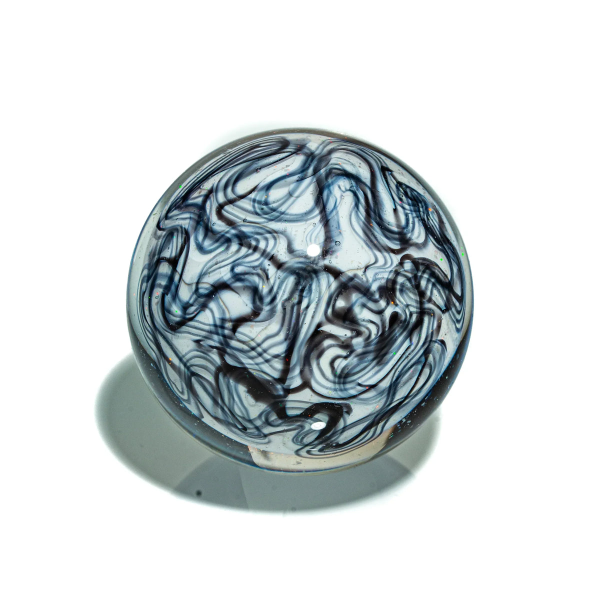 Clear glass marble with swirling black and white patterns on a white background