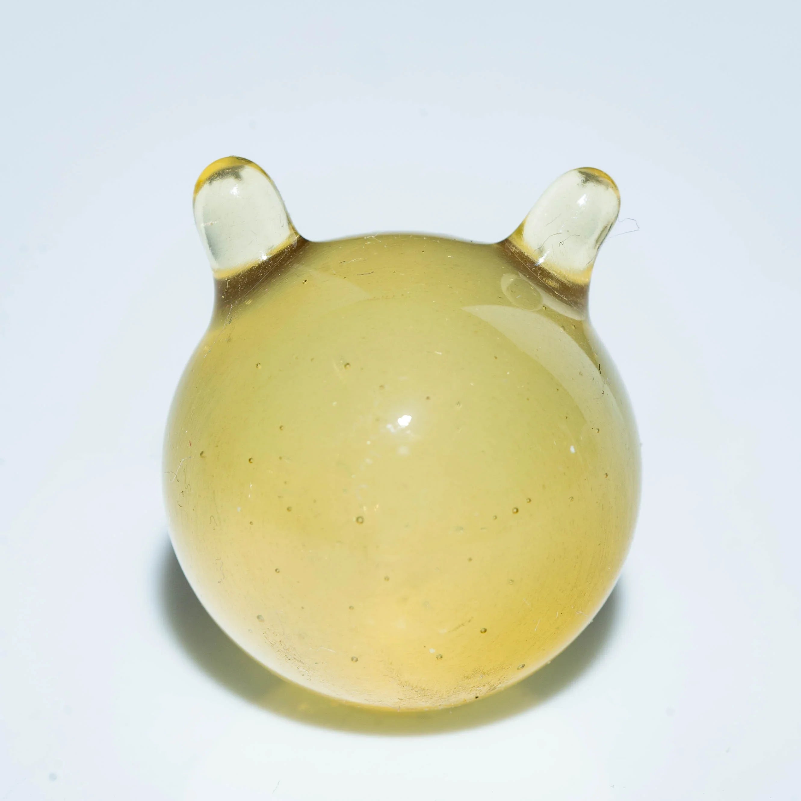 Round yellow glass carb cap with two ear-like handles on a white background