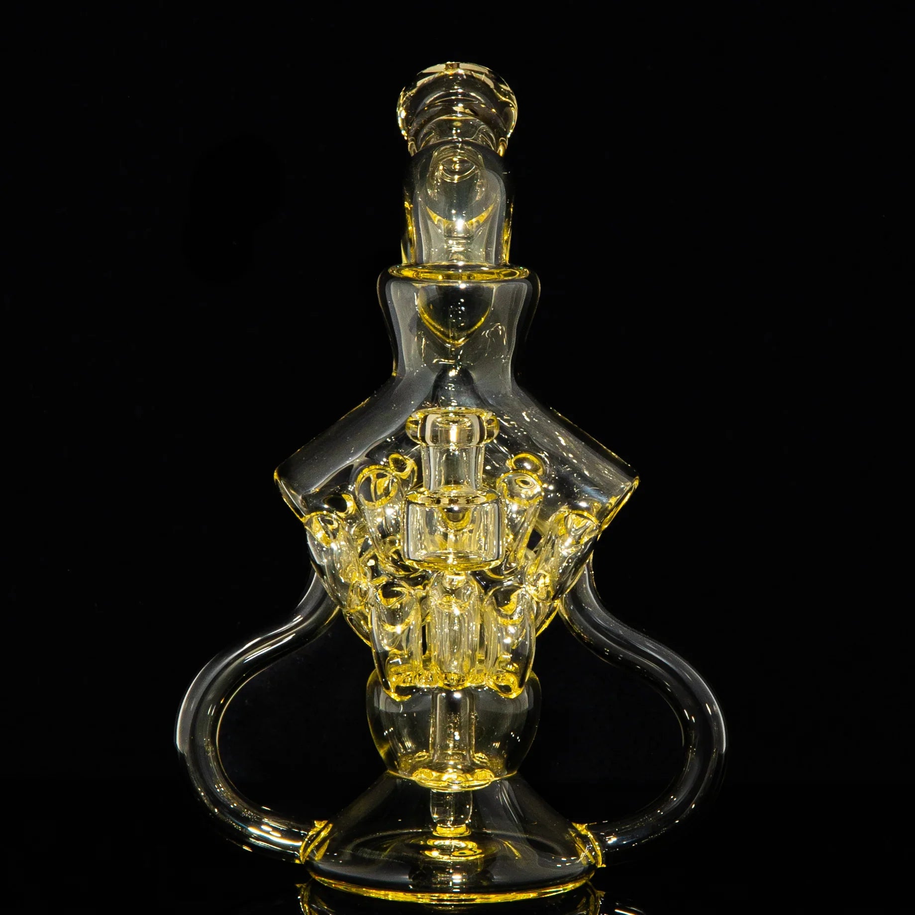 Intricate yellow-tinted glass water pipe with artistic design on black background