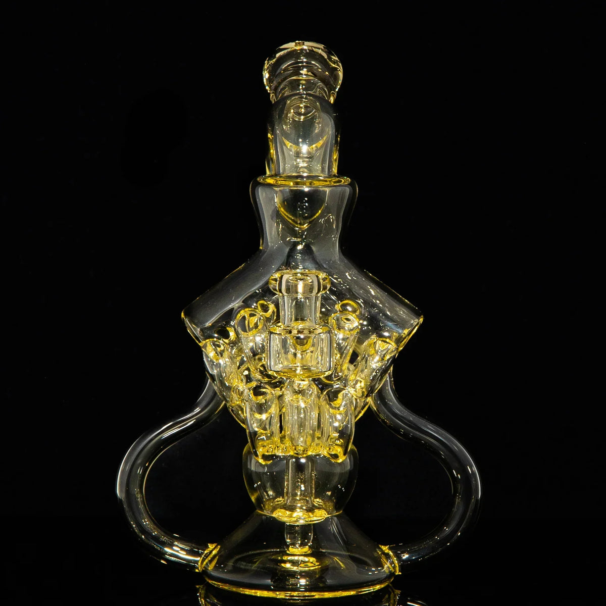 Intricate yellow-tinted glass water pipe with artistic design on black background