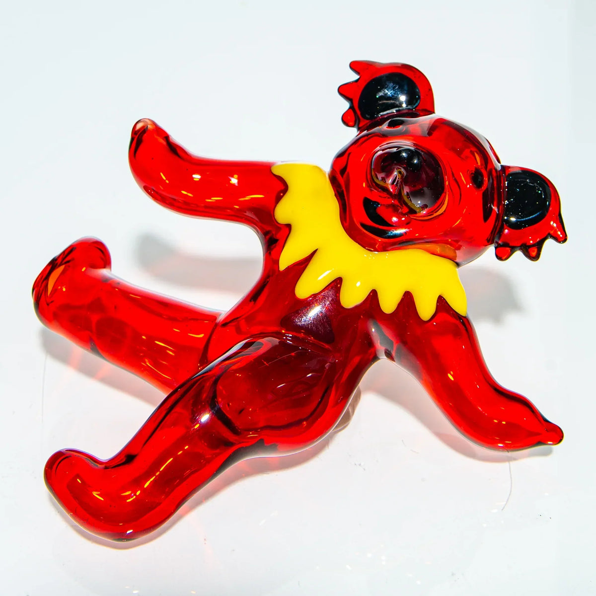 Hand-blown red glass bear figurine with yellow collar, displayed on white background.