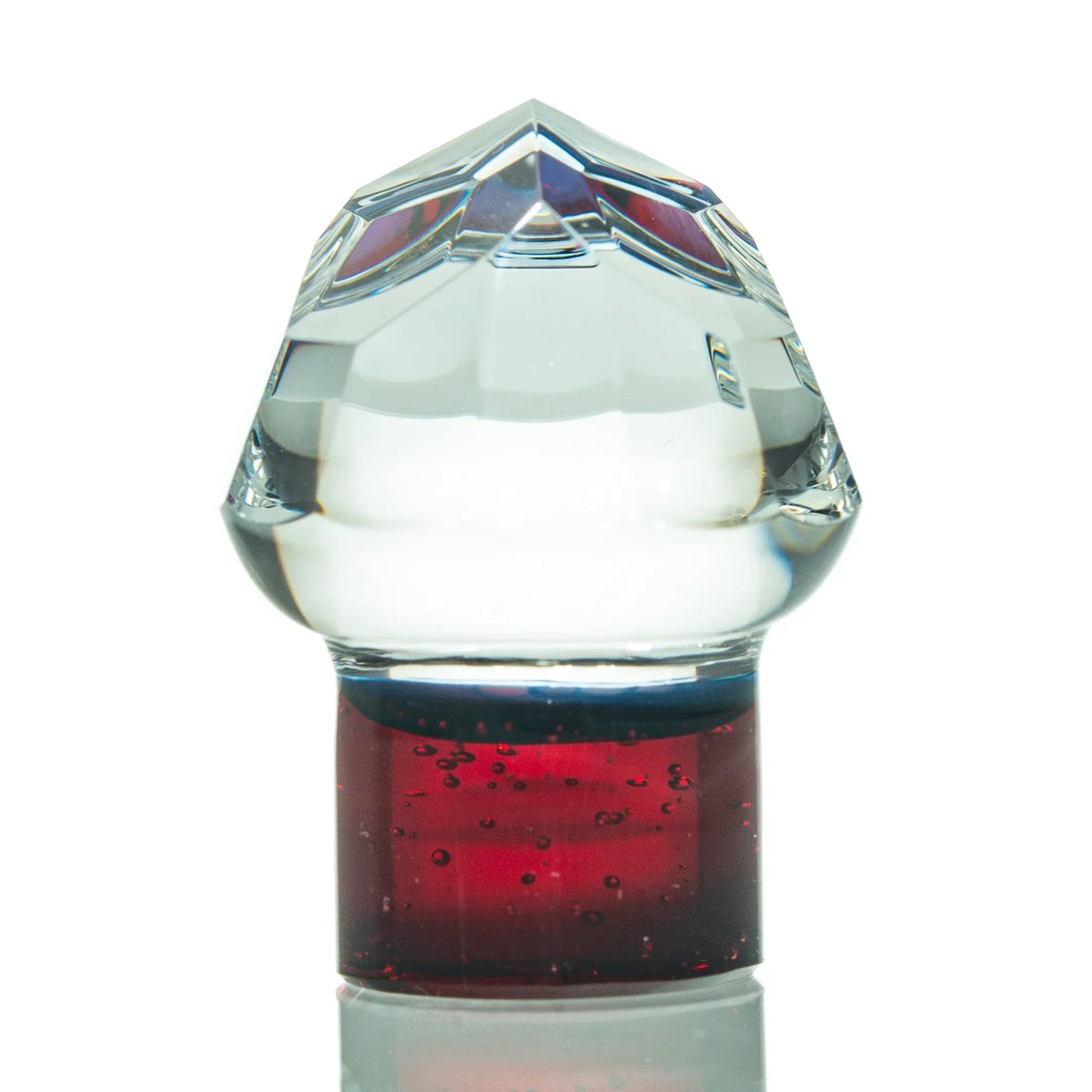 Clear glass carb cap with faceted top and red base, dab rig accessory on white background