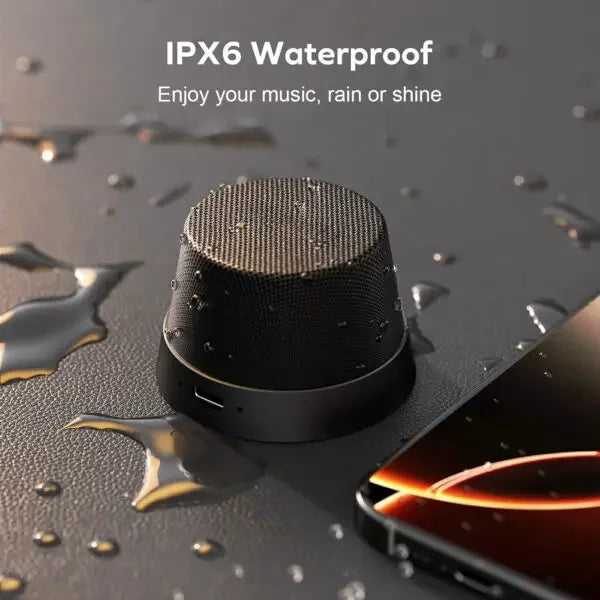IPX6 waterproof portable Bluetooth speaker next to smartphone with water droplets