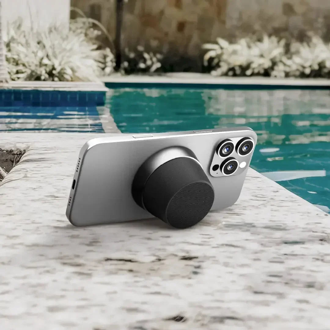 Smartphone with a black magnetic grip and stand on a marble poolside surface