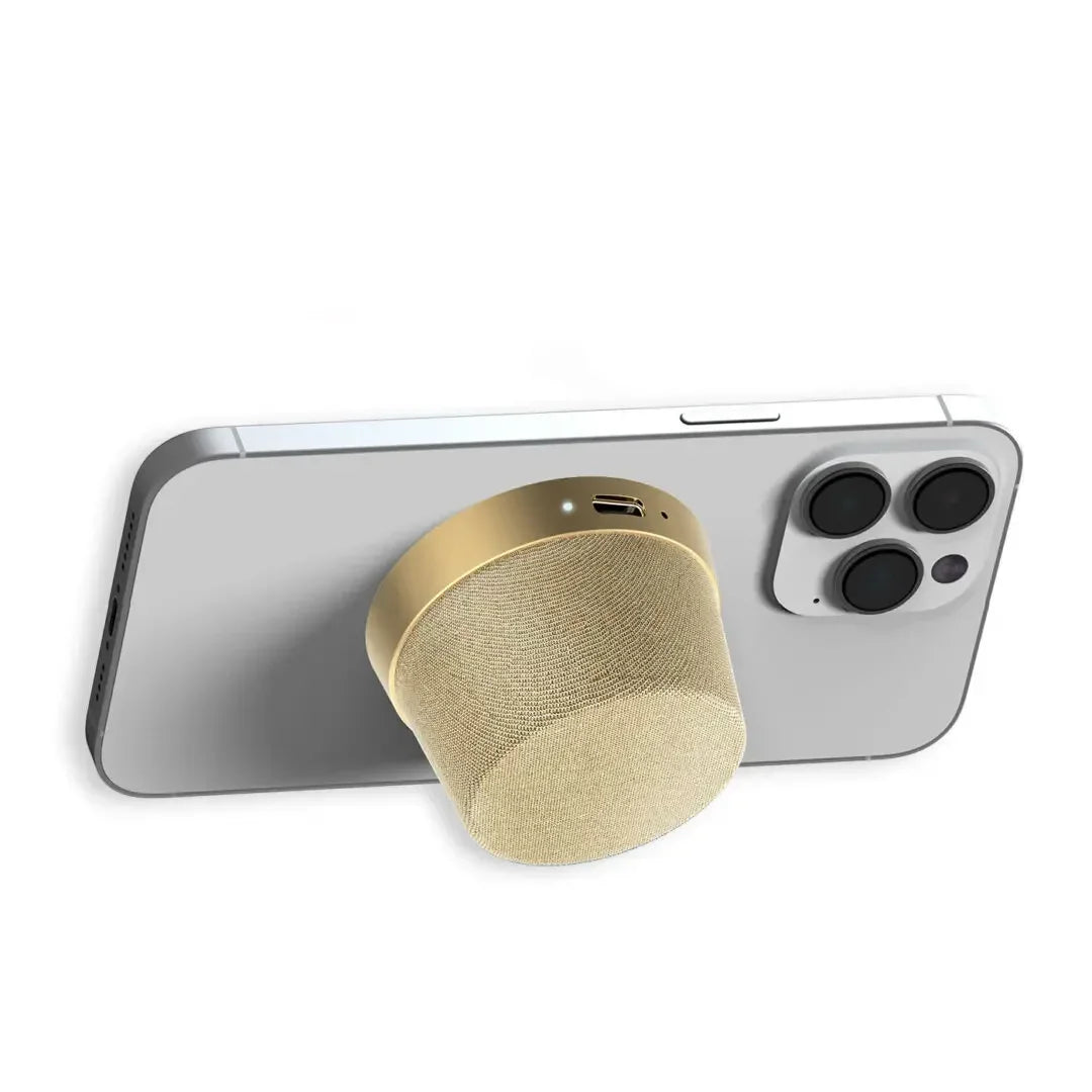 Gold portable mini speaker attached to the back of a smartphone with dual cameras