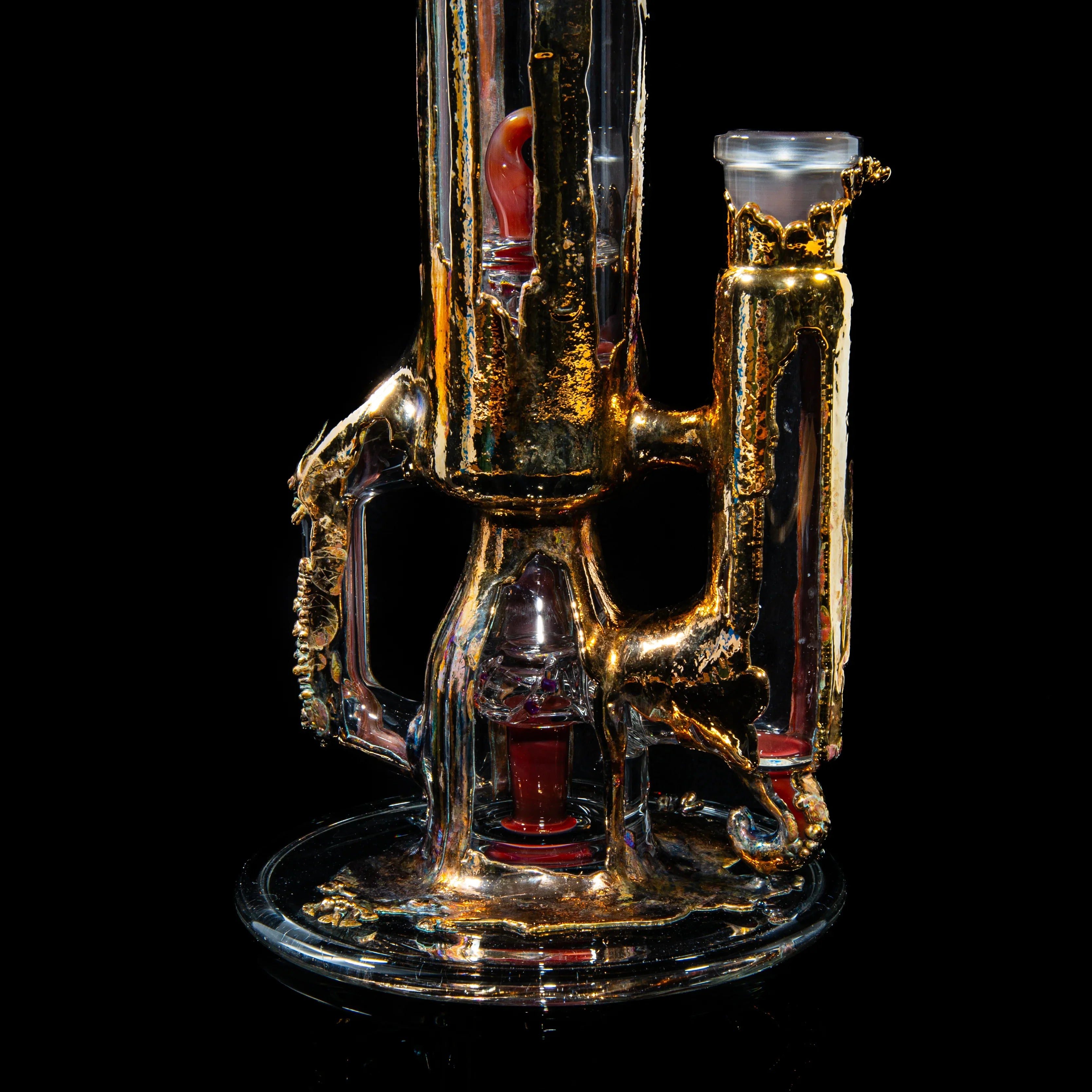 Heady glass water pipe with intricate gold accents and red details on a black background