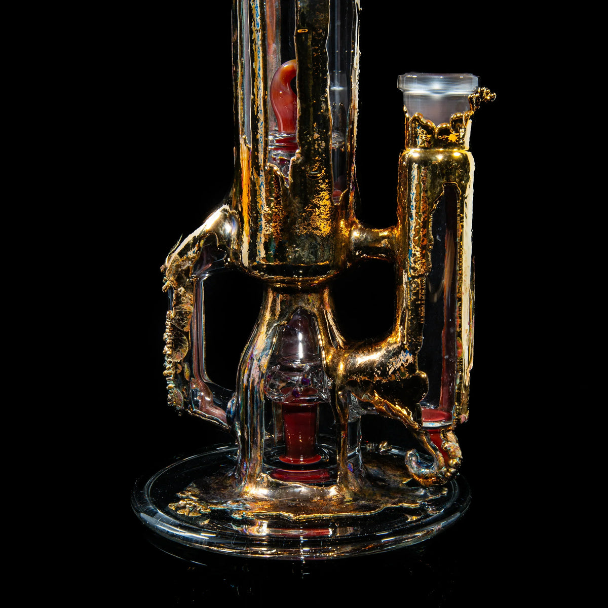 Heady glass water pipe with intricate gold accents and red details on a black background