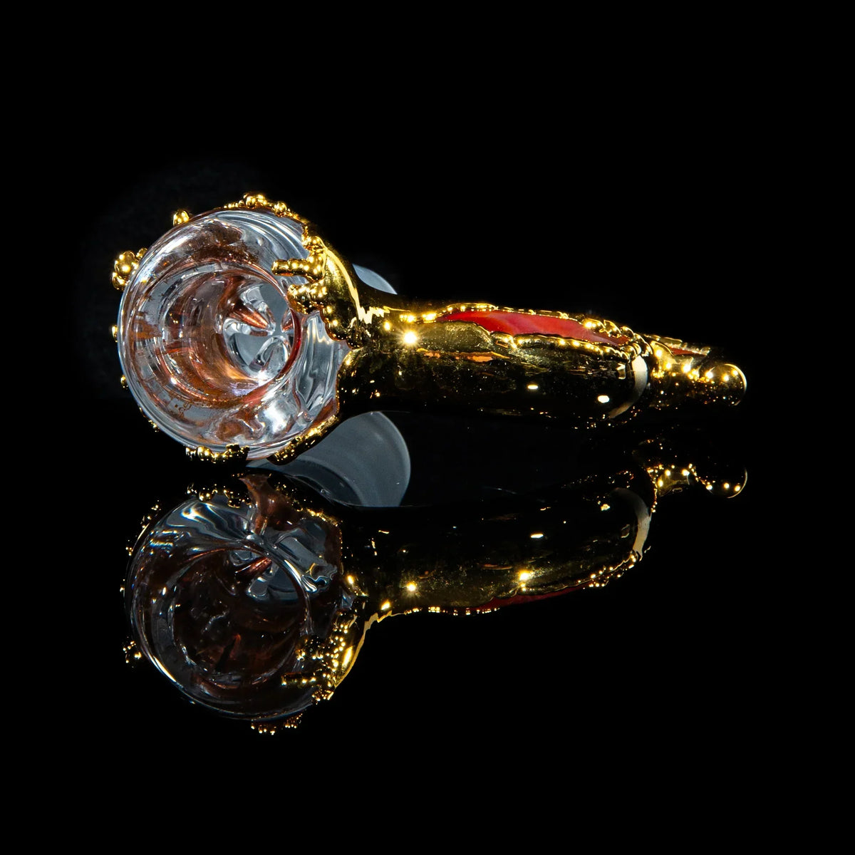 Gold and clear glass hand pipe with reflective black background