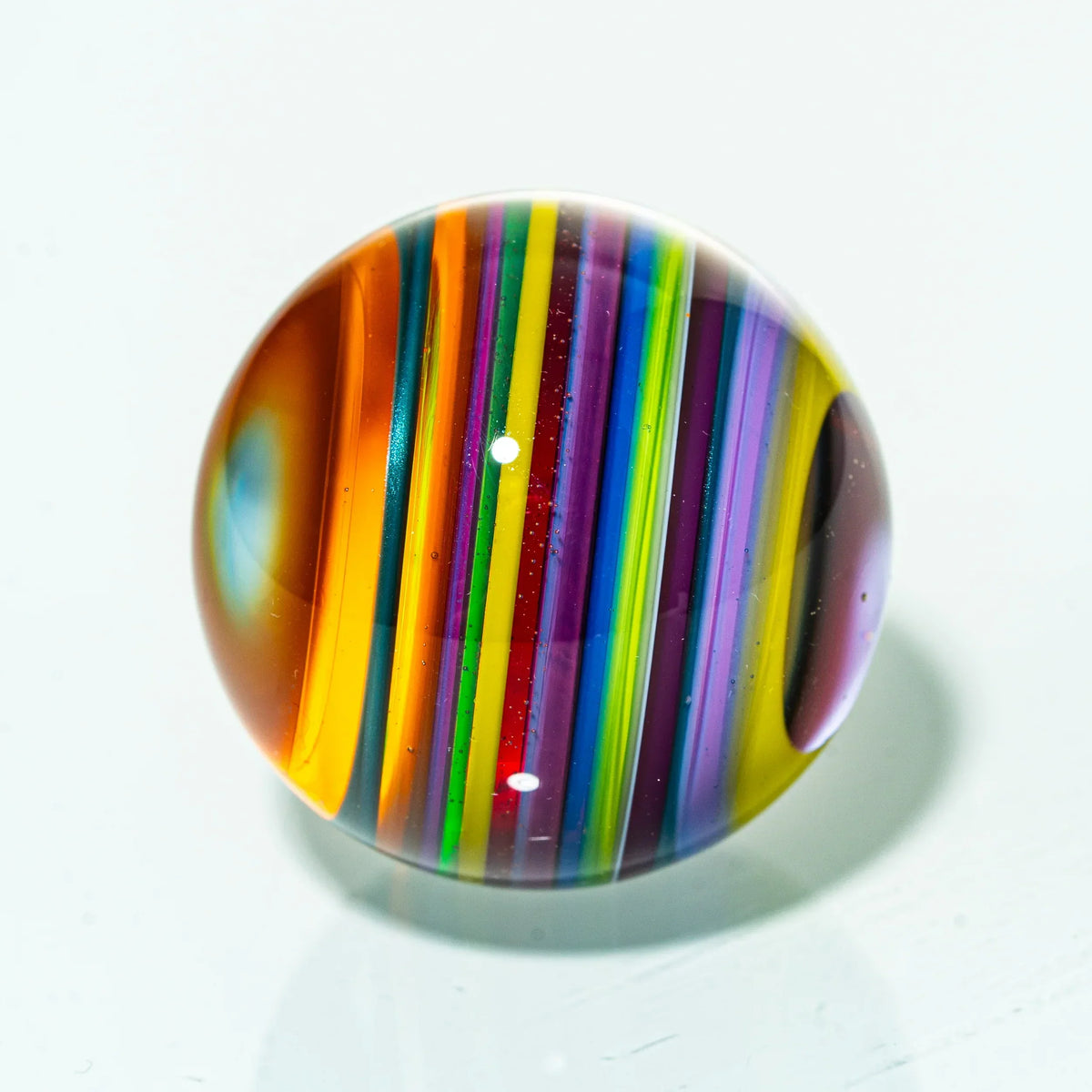 Colorful glass marble with vibrant rainbow stripes on a white background
