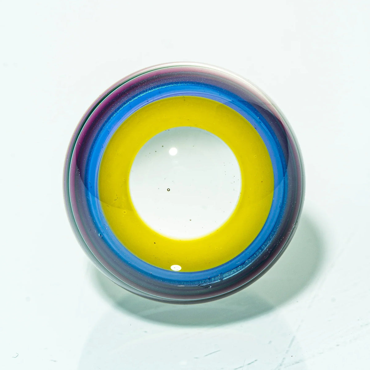 Colorful glass marble with yellow, blue, and purple rings on a white background
