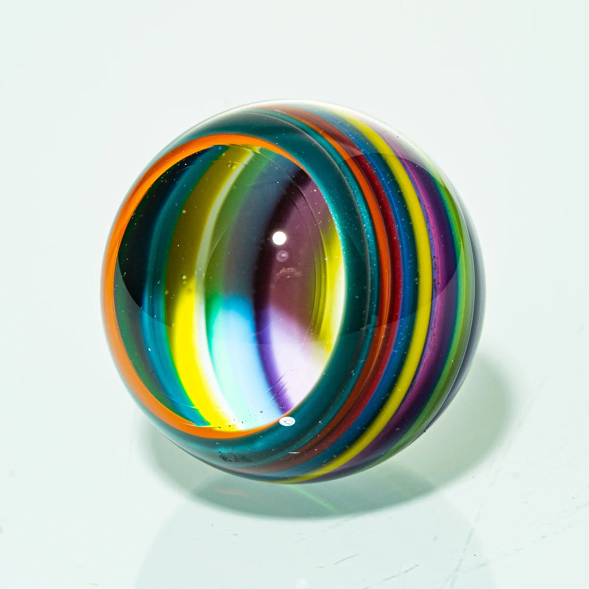Colorful glass marble with vibrant swirling rainbow stripes on white background