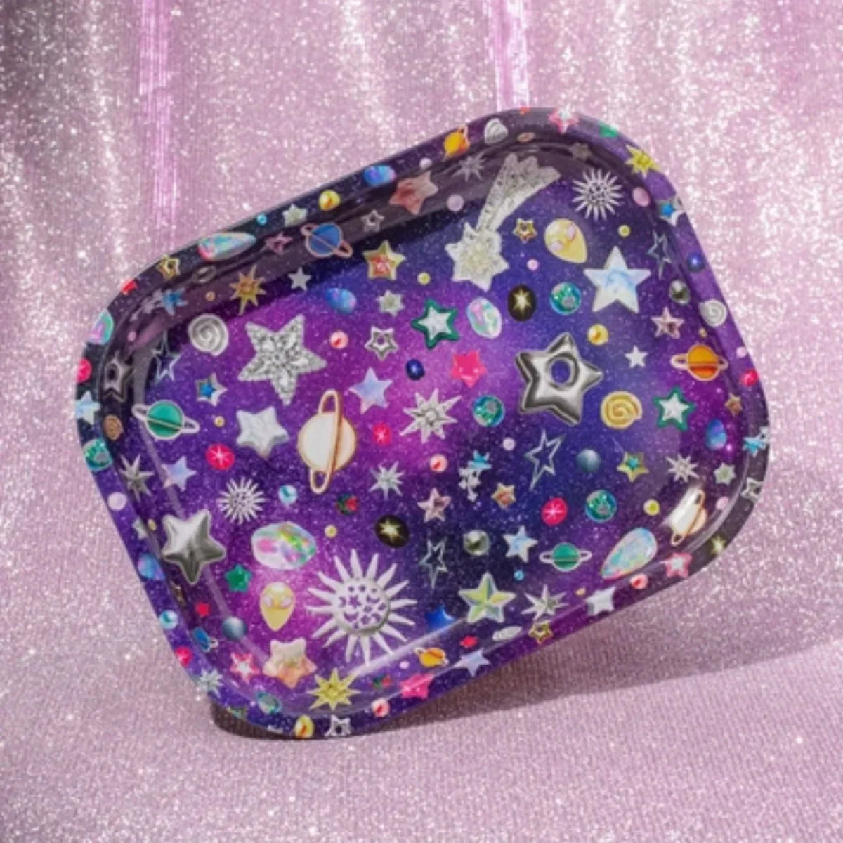 Colorful galaxy-themed rolling tray with stars and planets design on a glittery pink background