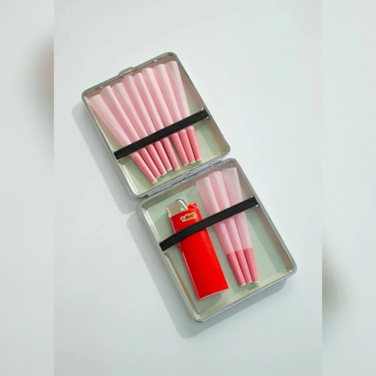 Metal case with pink pre-rolled cones and a red lighter, smoking accessories display