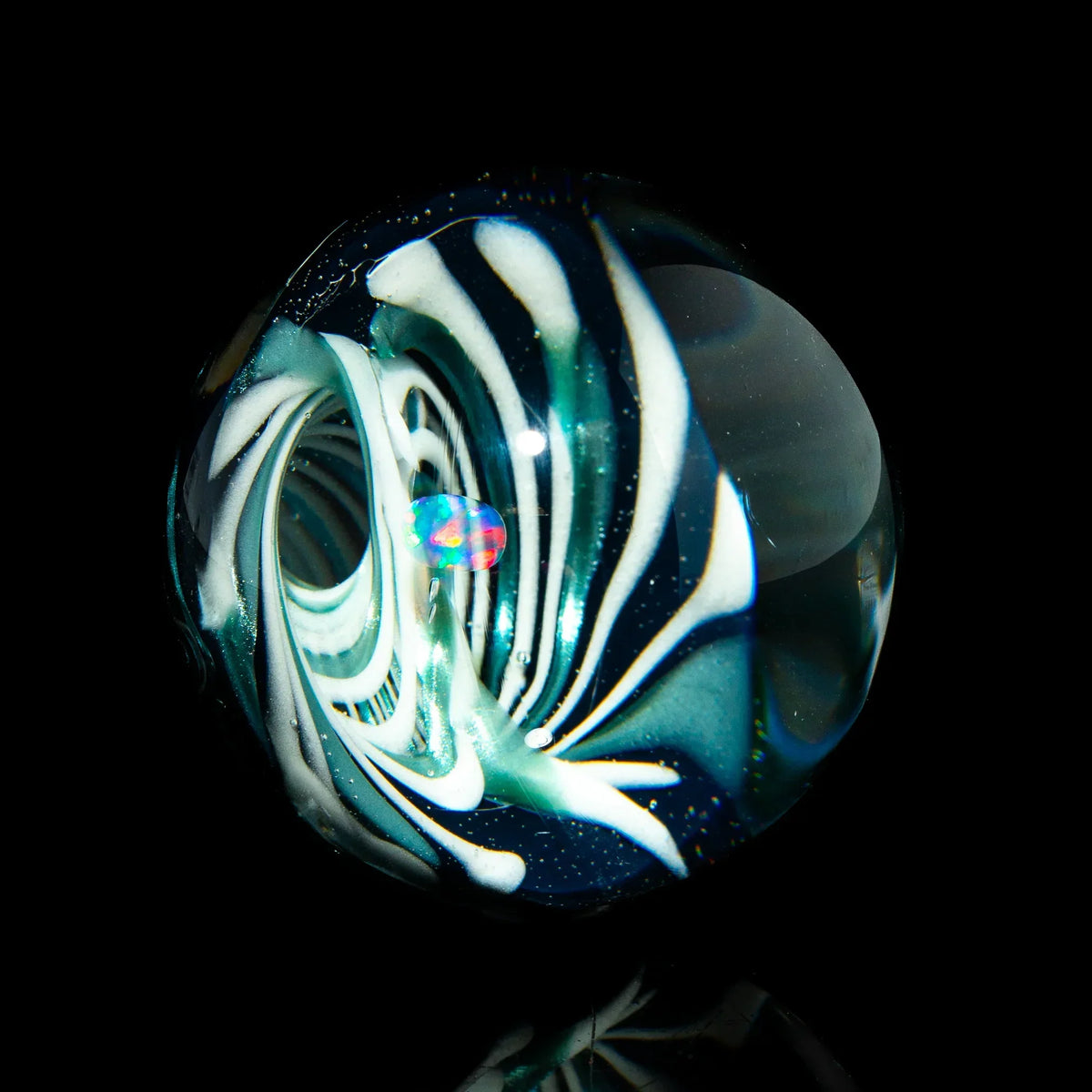 Handcrafted glass marble with swirling white and teal patterns and an opal core on black background