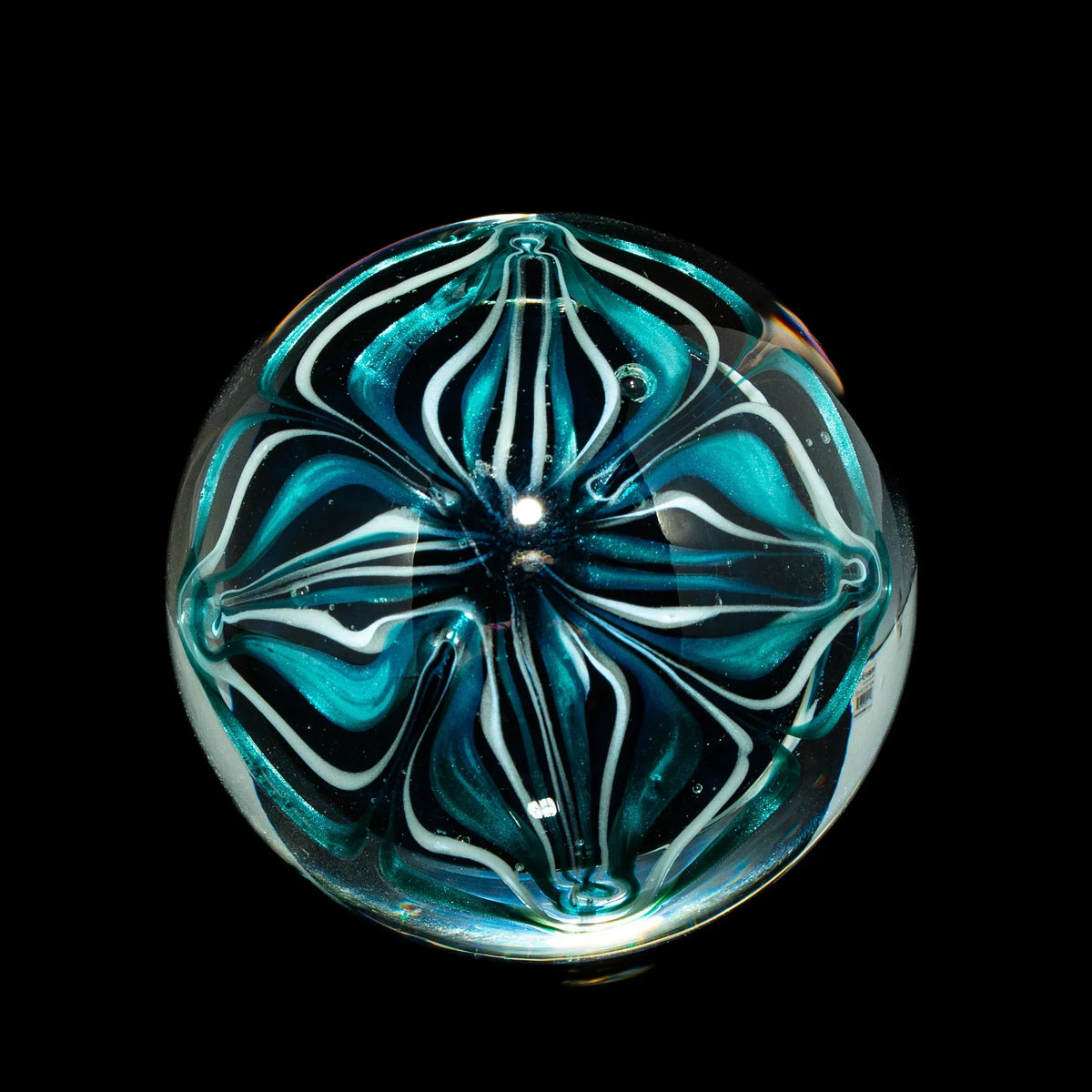 Hand-blown glass marble with teal and white swirl design on black background