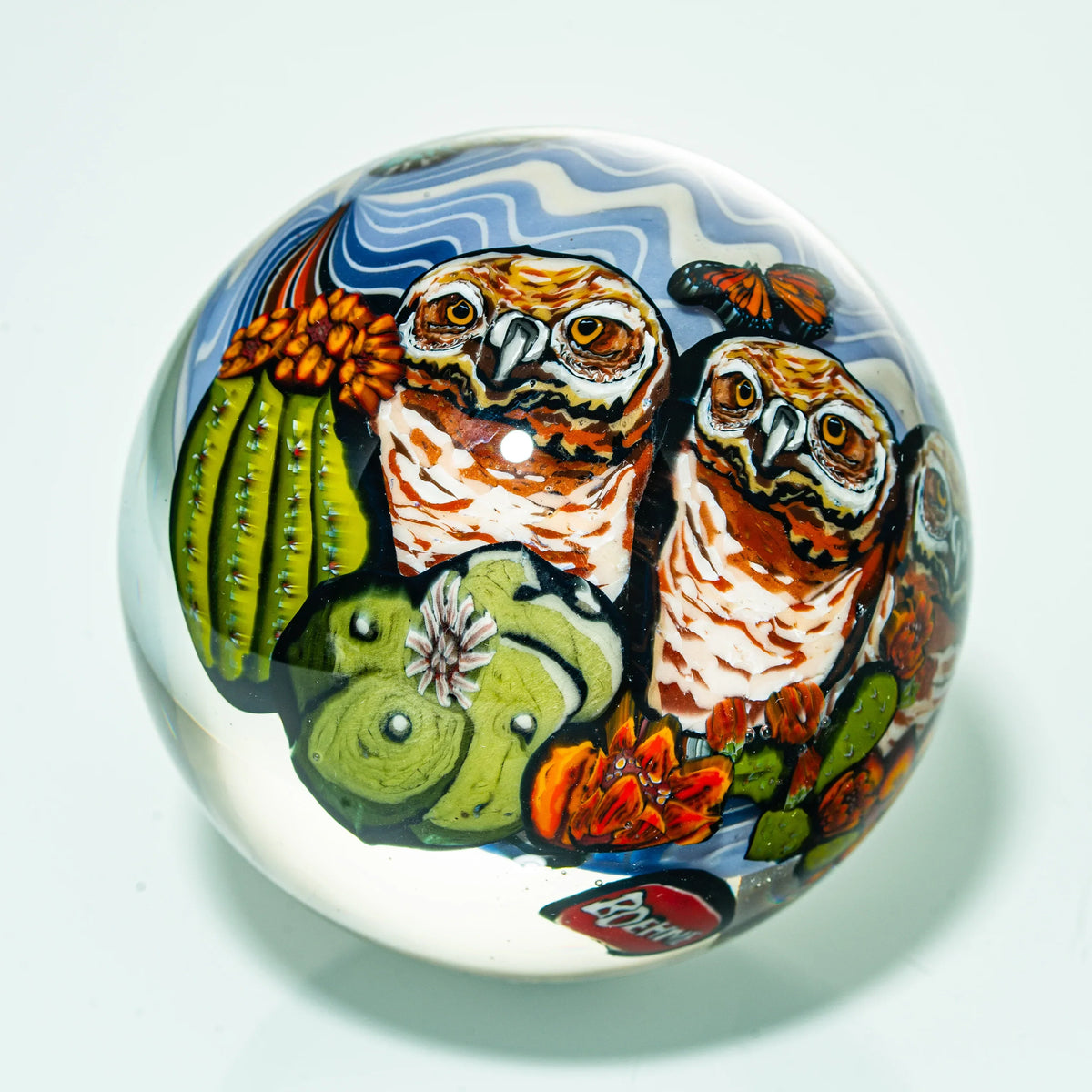 Glass art marble featuring two owls, colorful cacti, and flowers with detailed designs