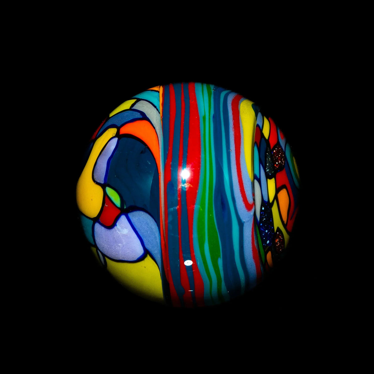 Colorful hand-blown glass marble with abstract rainbow patterns against black background