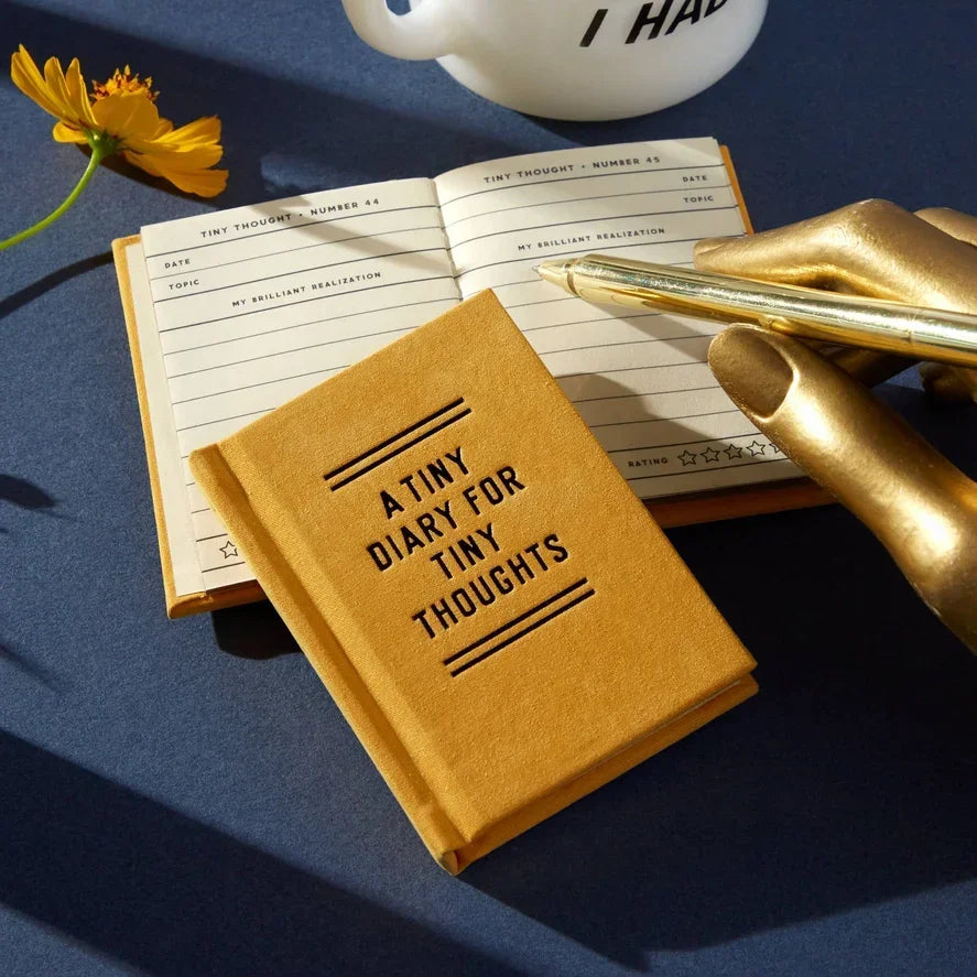 Tiny yellow diary titled 'A Tiny Diary for Tiny Thoughts' with open journal and pen