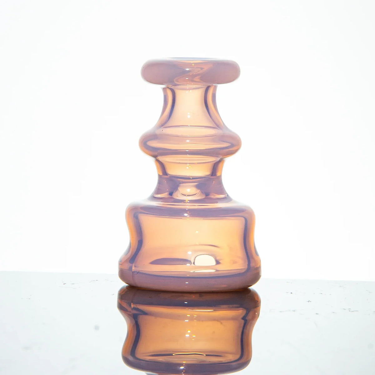 Purple glass carb cap with a sculpted design displayed on a reflective surface