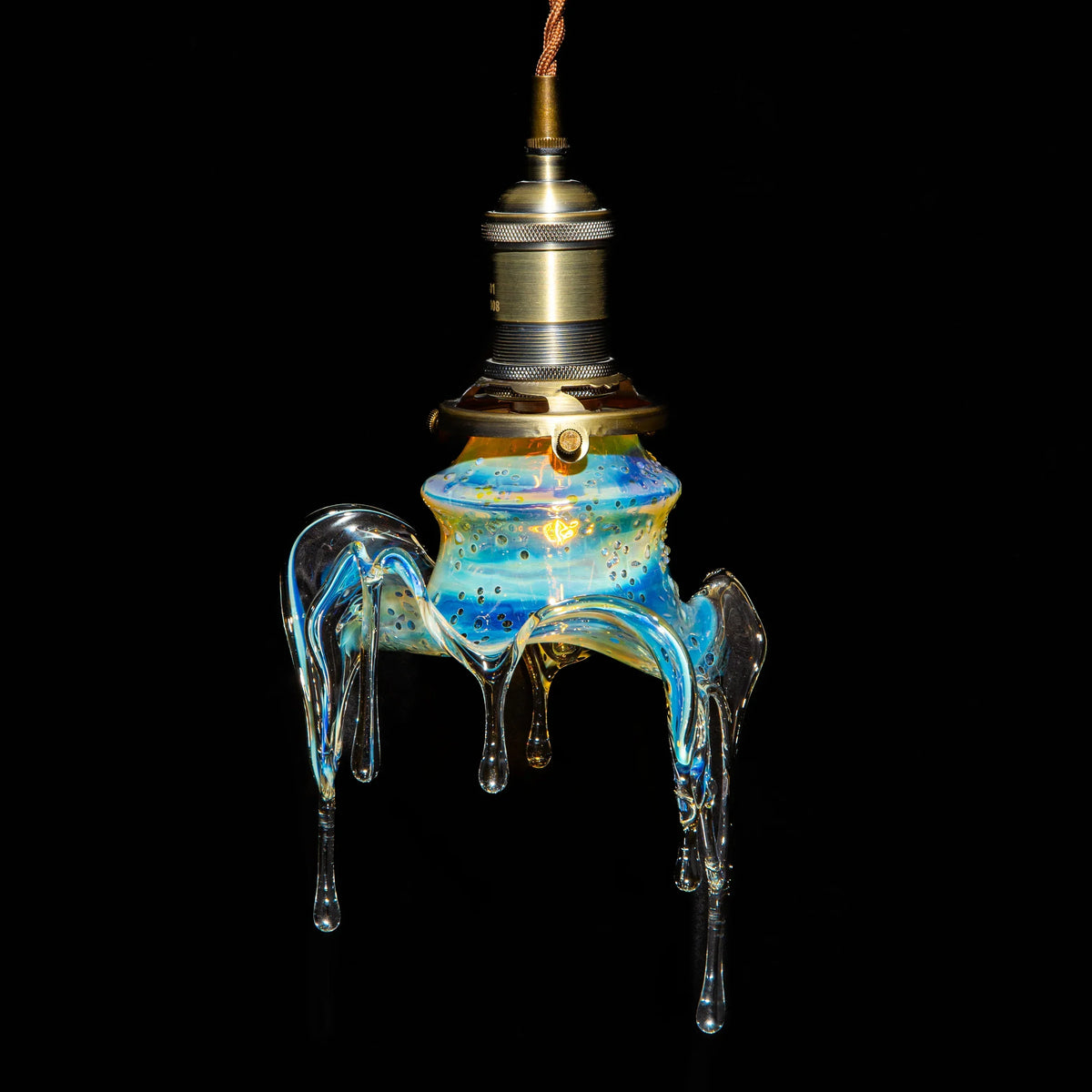 Hand-blown glass pendant light with blue and gold details, unique dripped design, black background