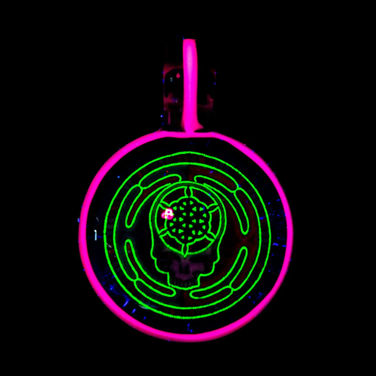 UV-reactive glass pendant with neon pink and green skull labyrinth design on black background