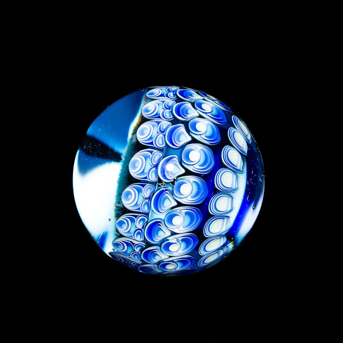 Hand-blown blue glass marble with intricate swirling patterns on black background