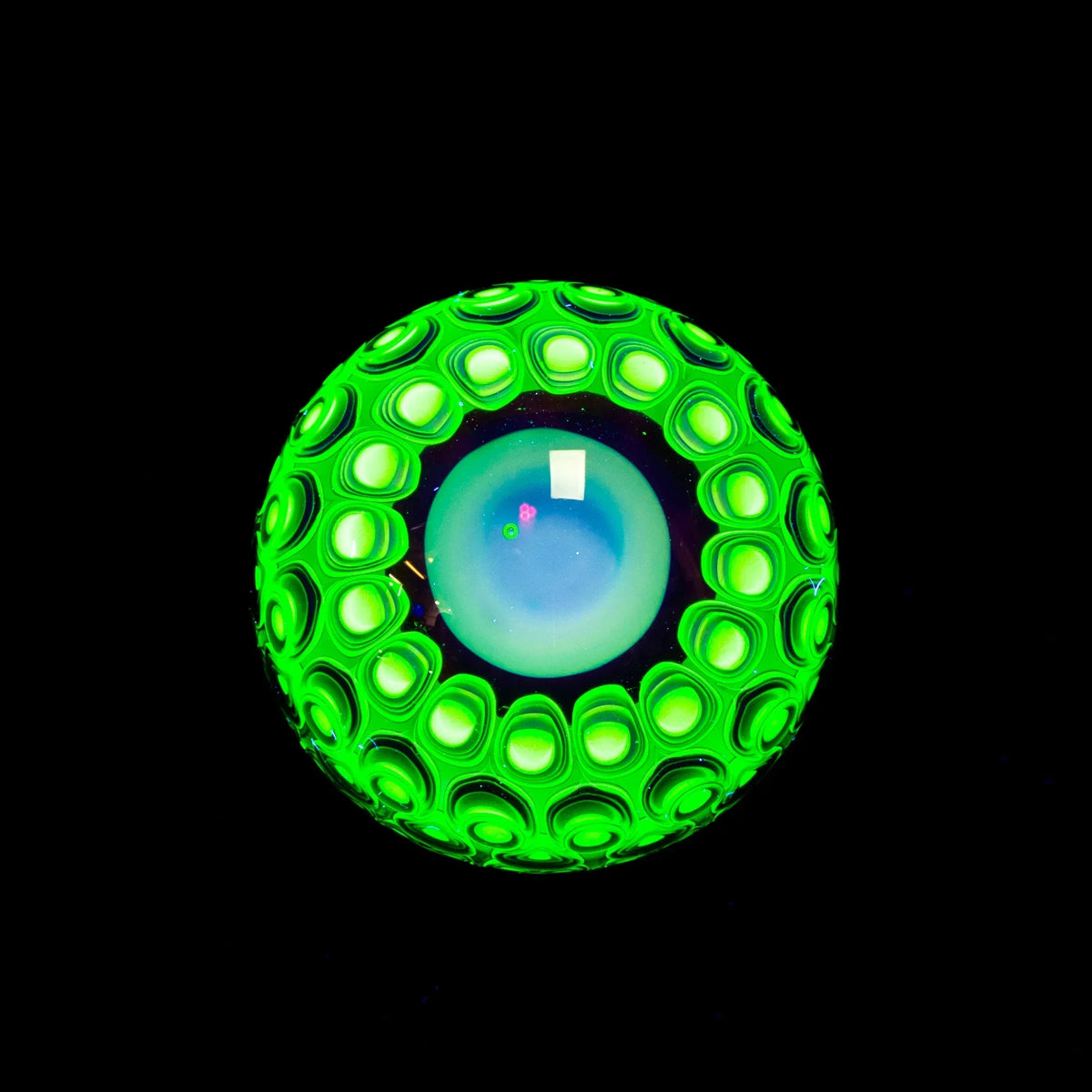 Intricate green glass marble with textured patterns and a luminous center on black background.