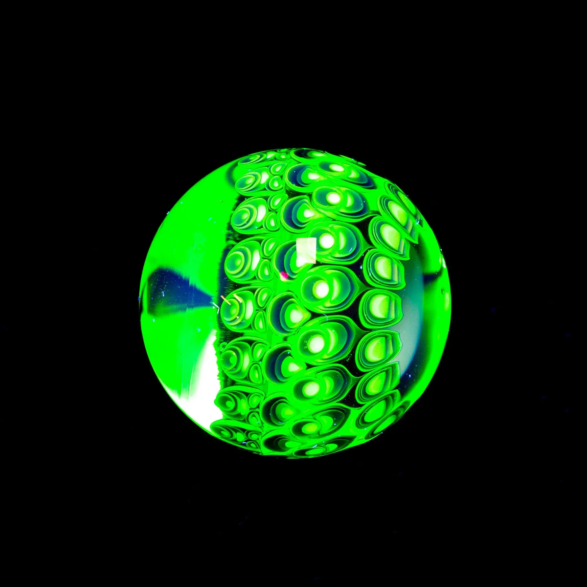 Glowing green glass marble with intricate bubble patterns on a black background
