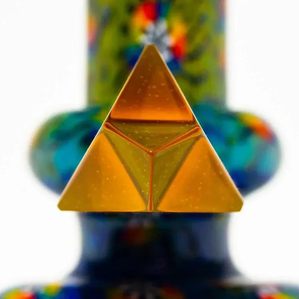 Close-up of a colorful glass mini water pipe with gold pyramid detail and vibrant patterns