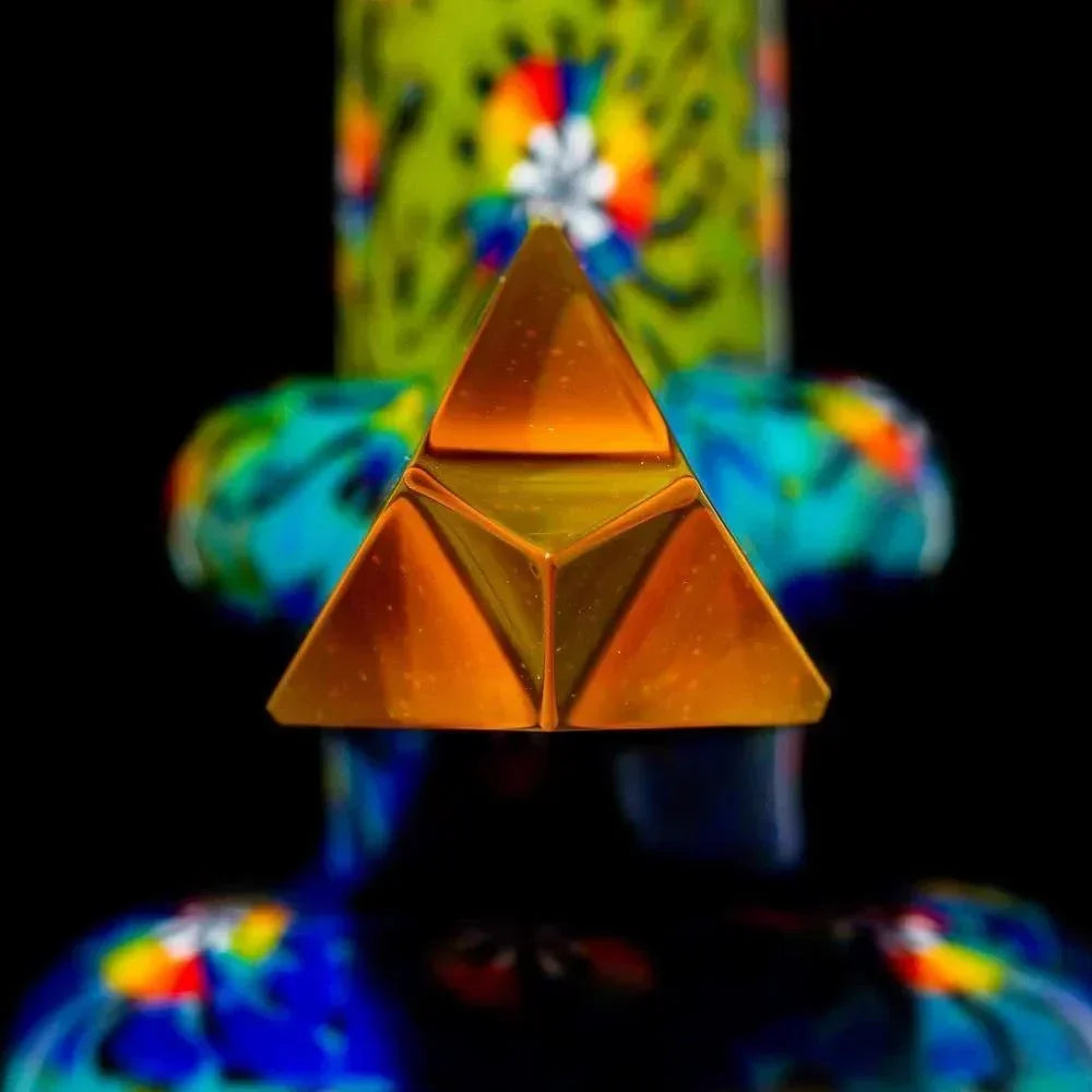 Close-up of a glass mini tube with golden pyramid accent and colorful patterns