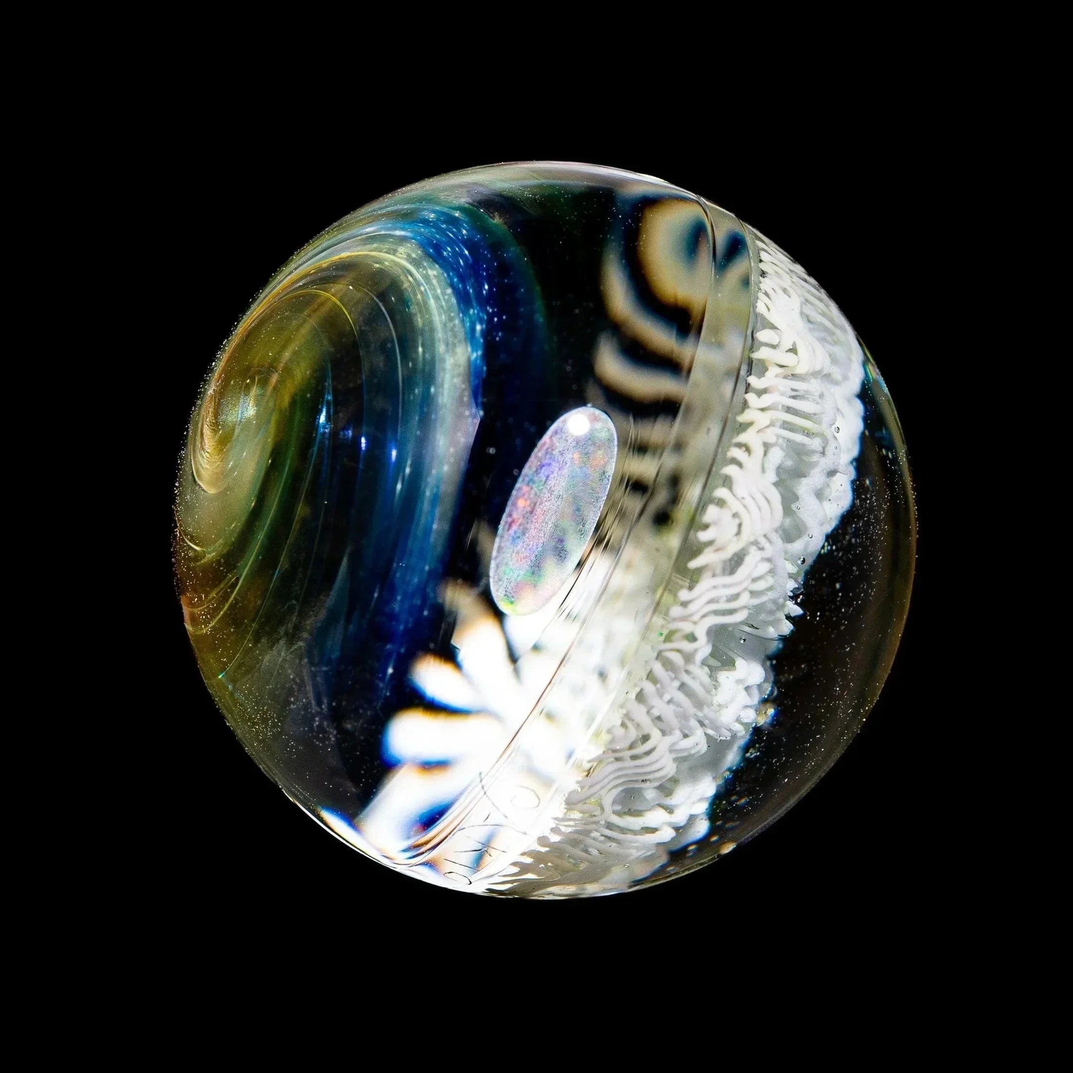 Marble glass art sphere with opal inlay, blue swirls, and white intricate design on black background