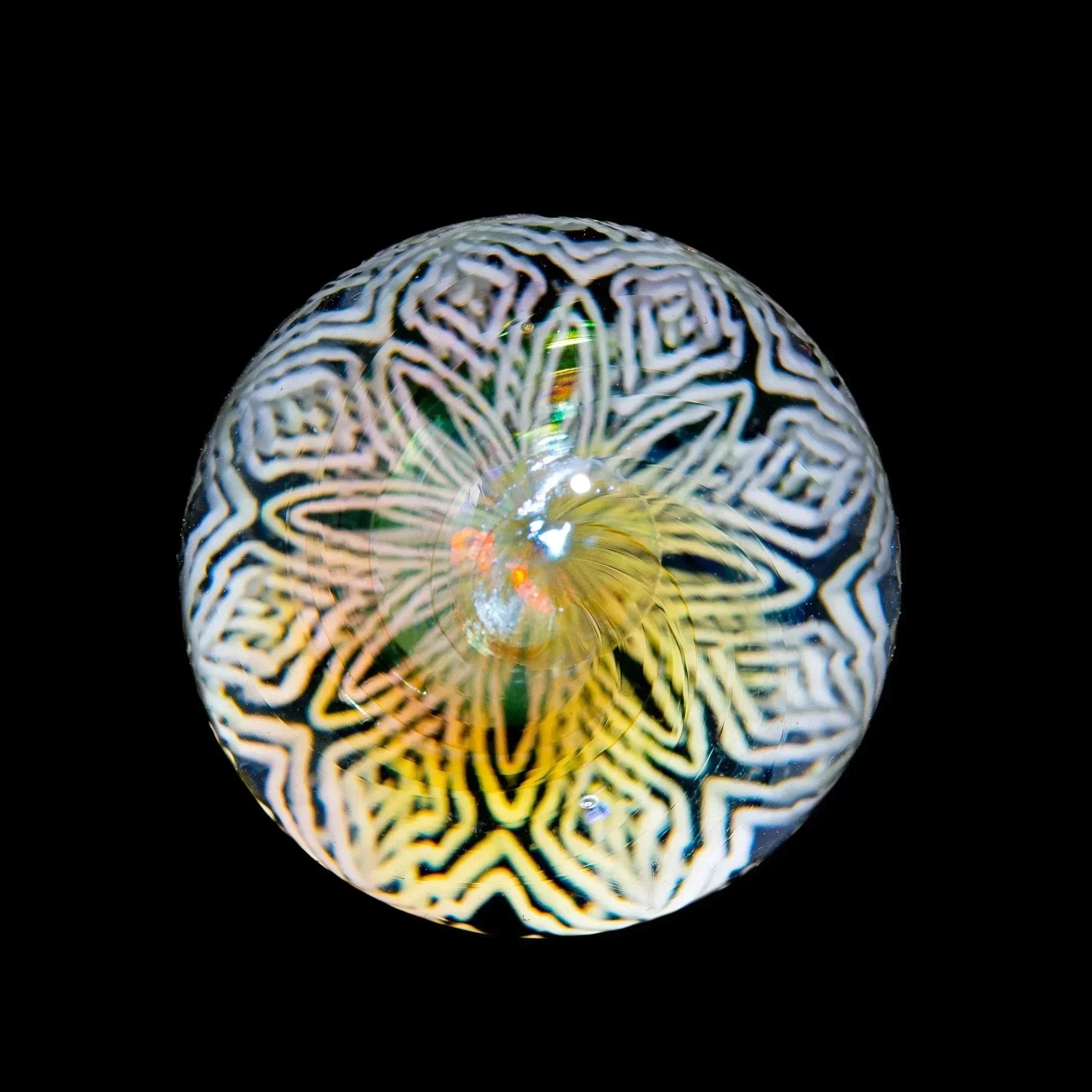 Intricate glass marble with geometric and opal pattern on a black background