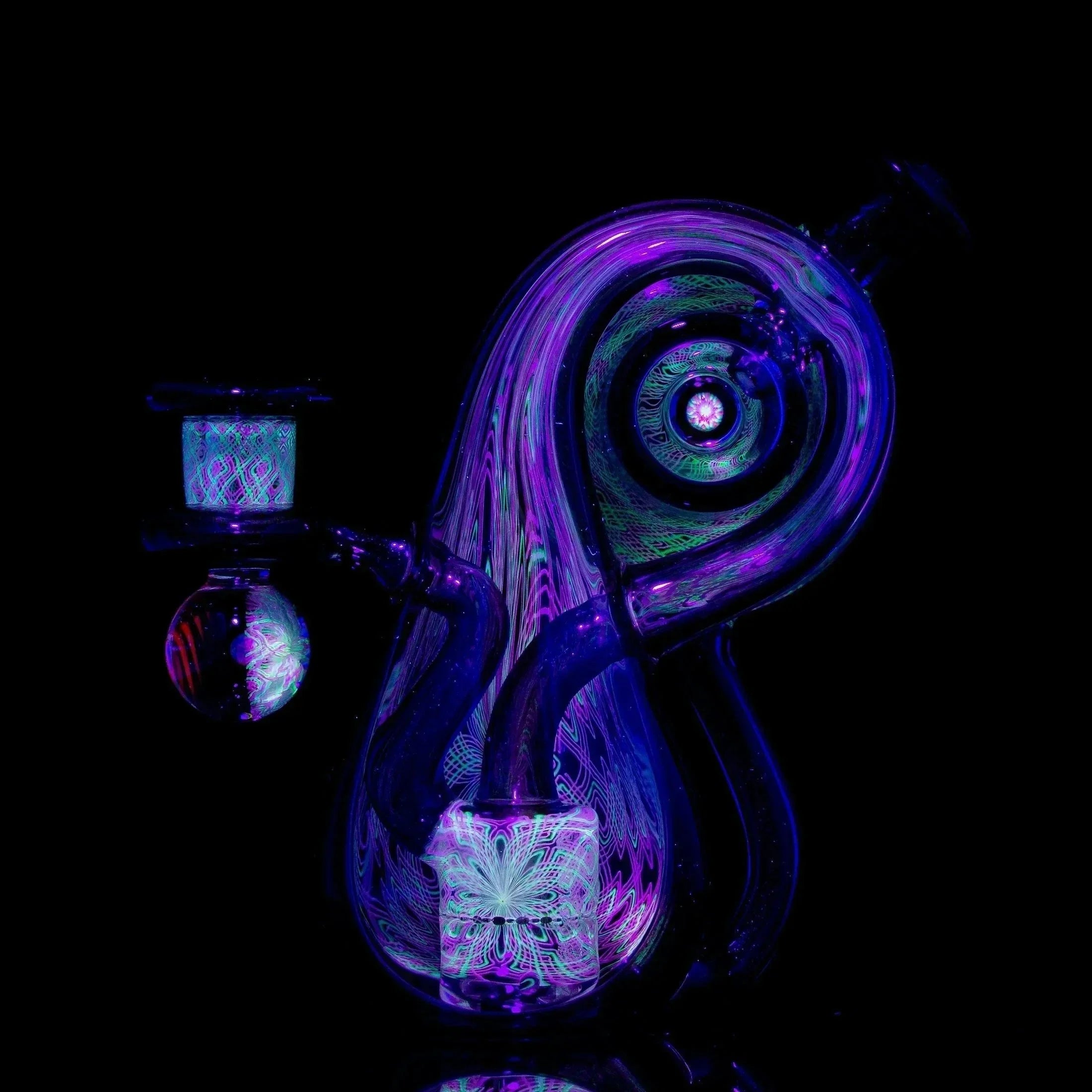 UV reactive heady glass rig with intricate colorful patterns on a black background