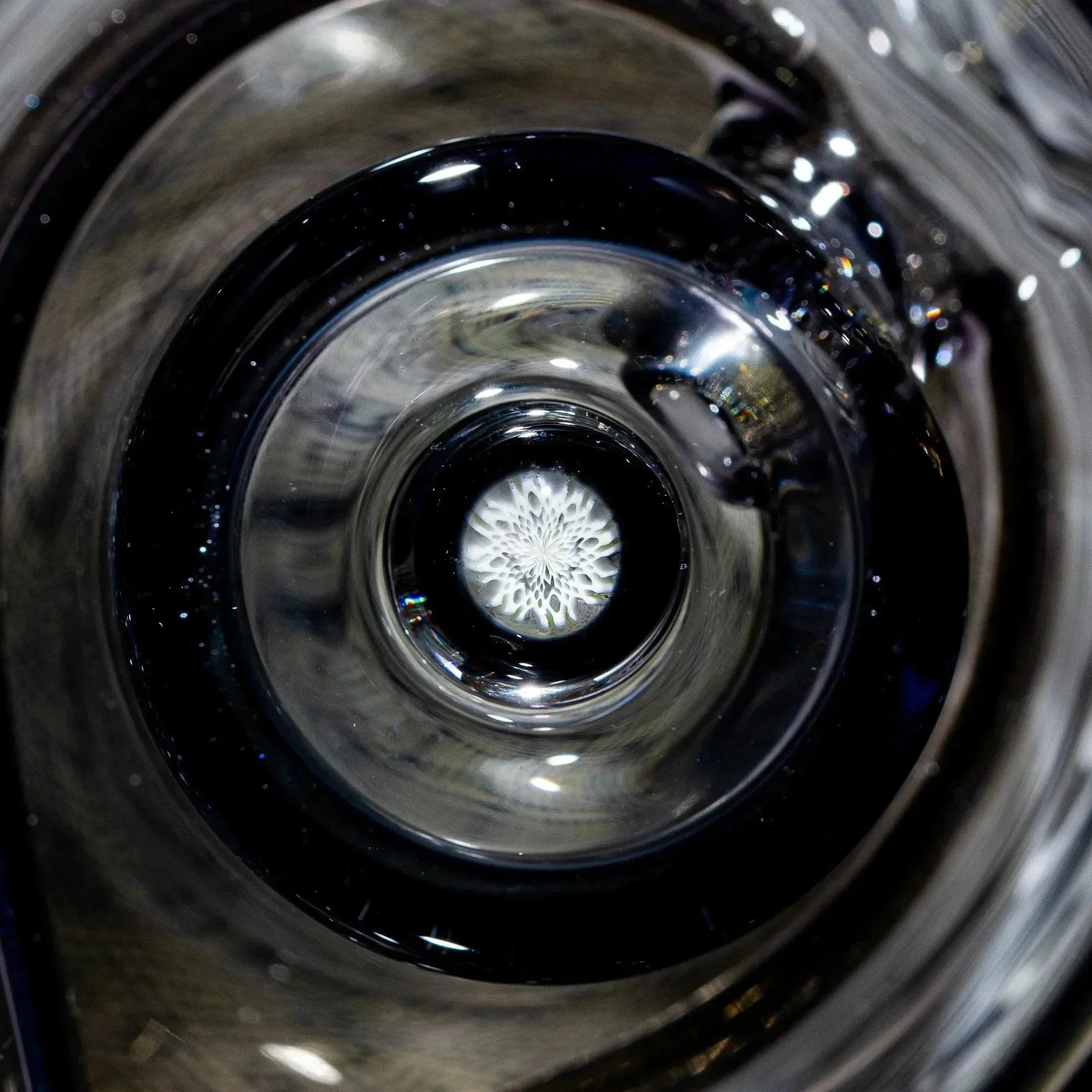Close-up of decorative glass art with intricate white flower pattern inside clear glass.