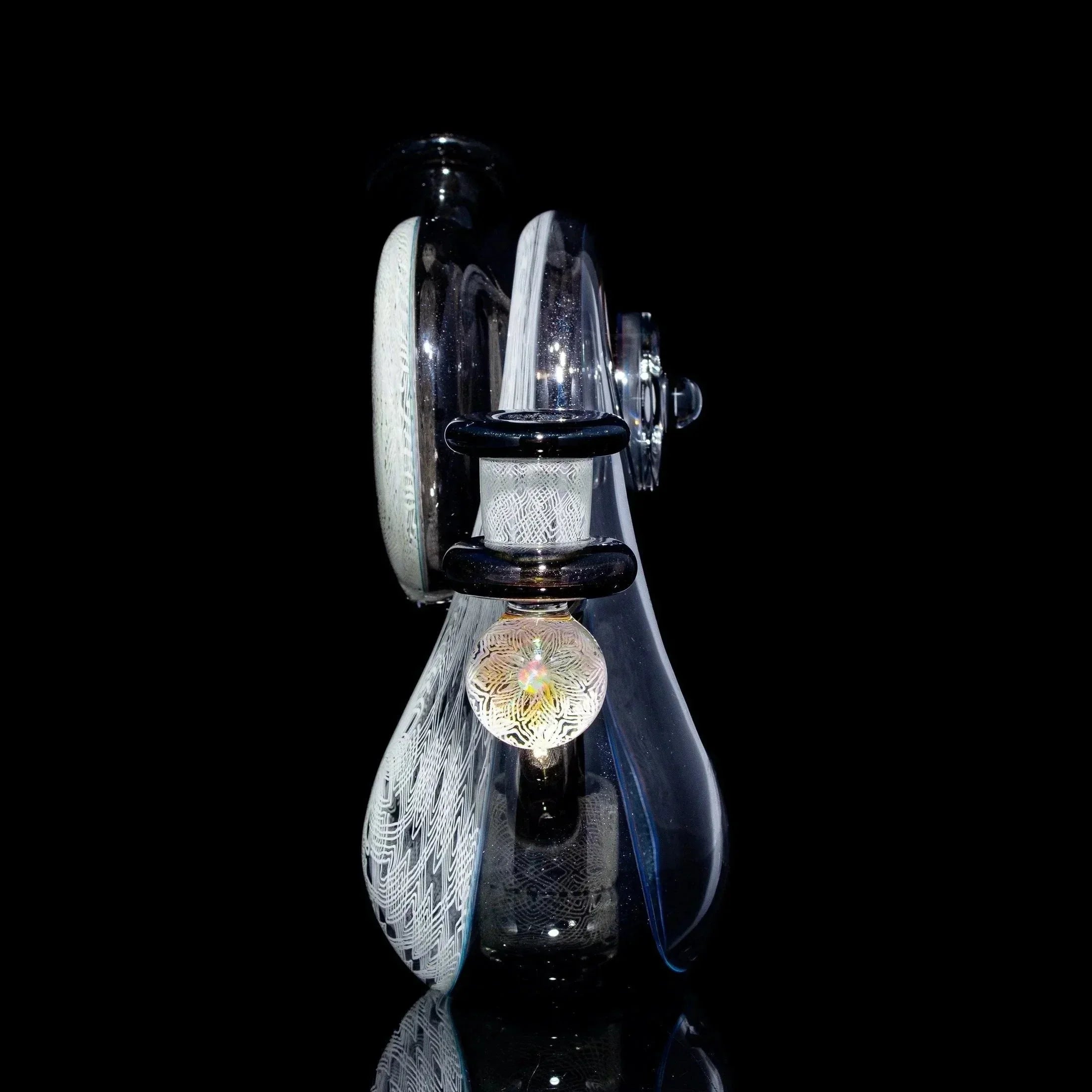 Intricate clear glass water pipe with decorative patterns and opal marble on black background.