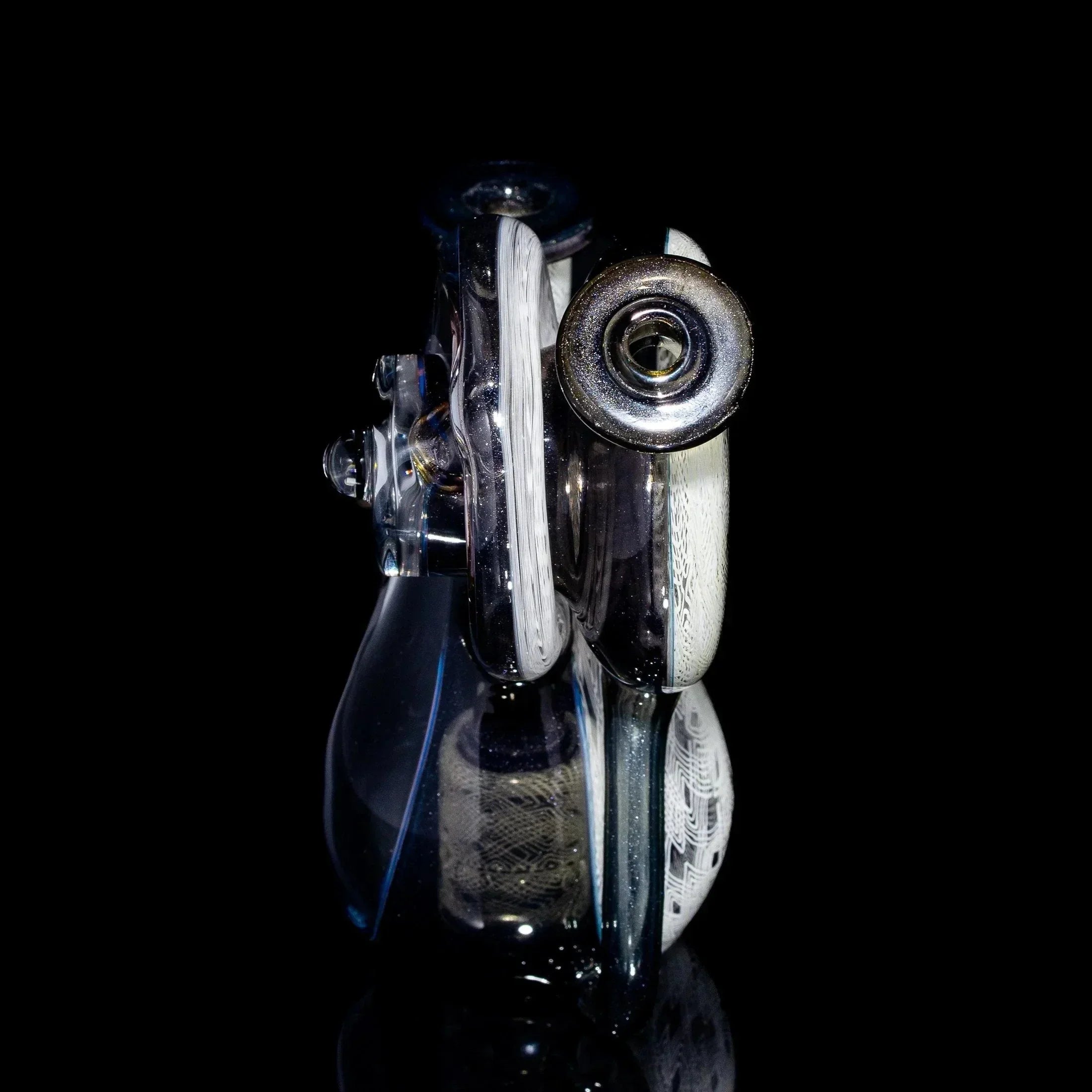 Intricate clear and white heady glass pipe with artistic patterns on a black background