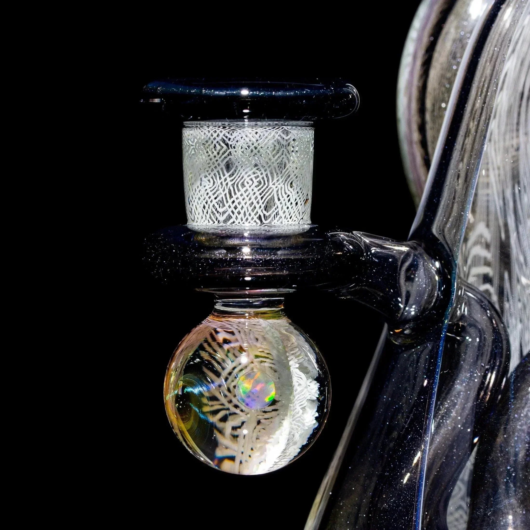 Close-up of intricate glass art water pipe attachment with detailed linework and opal accents