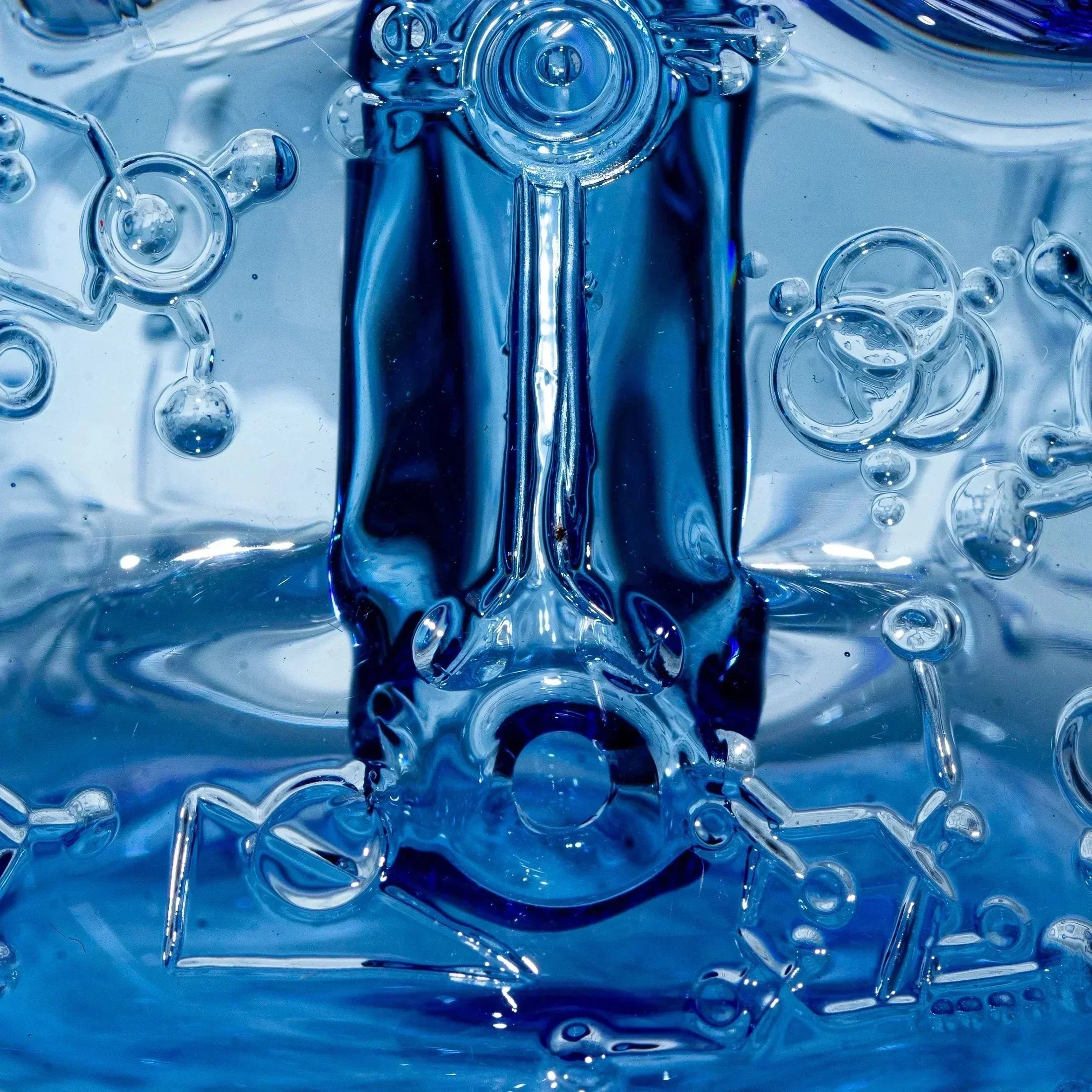 Close-up of detailed blue glass art with molecular and bubble patterns
